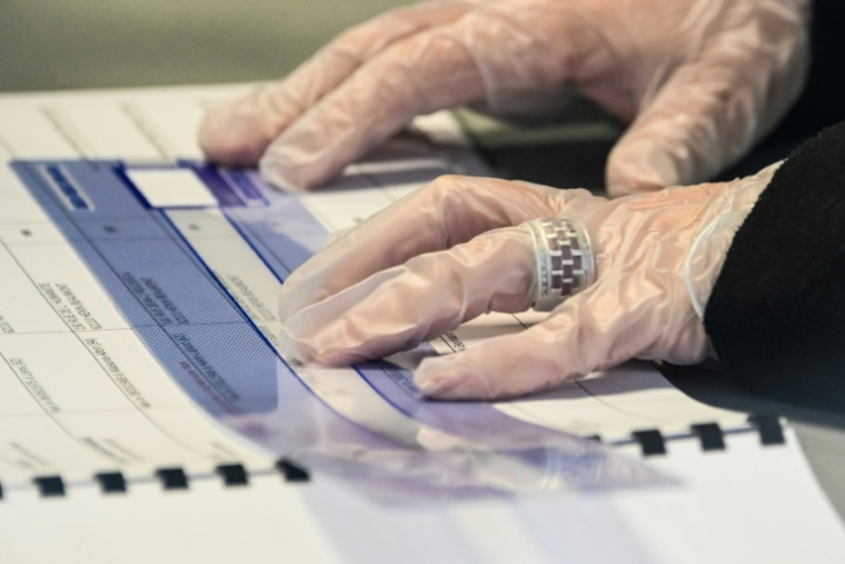 Une personne portant des gants tient un registre dans un bureau de vote lors du premier tour des élections municipales, le 15 mars 2020 à Hénin-Beaumont ( AFP / DENIS CHARLET )