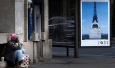 Une personne sans abri à Paris, devant une publicité pour une marque de luxe, le 8 juillet 2025 ( AFP / JOEL SAGET )
