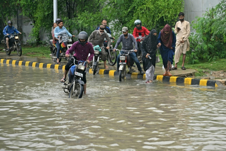 Des habitants tentent de passer à moto dans une rue inondée après de fortes pluies, le 10 septembre 2025 à Karachi, au Pakistan ( AFP / Rizwan TABASSUM )