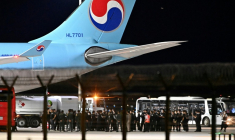 Des policiers cambodgiens et sud-coréens près de l'avion affrété pour rapatrier la soixantaine de Sud-Coréens soupçonnés d'implication dans des arnaques en ligne au Cambodge, à l'aéroport international de Techo,  le 17 octobre 2025 ( AFP / TANG CHHIN Sothy )