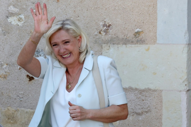 Marine Le Pen (c), cheffe du groupe parlementaire Rassemblement national (RN) et candidate à la présidentielle de 2027, salue ses sympathisants après une réunion de campagne à l'hôtel de ville de La Flèche, le 8 juillet 2026 dans la Sarthe ( AFP / FRED TANNEAU )