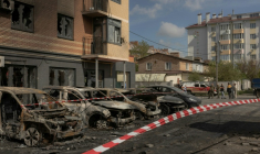 Des voitures calcinées devant un immeuble résidentiel endommagé par des frappes de drones et de missiles russes à Kiev, le 14 mai 2026 en Ukraine ( AFP / Roman PILIPEY )