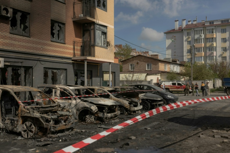 Des voitures calcinées devant un immeuble résidentiel endommagé par des frappes de drones et de missiles russes à Kiev, le 14 mai 2026 en Ukraine ( AFP / Roman PILIPEY )