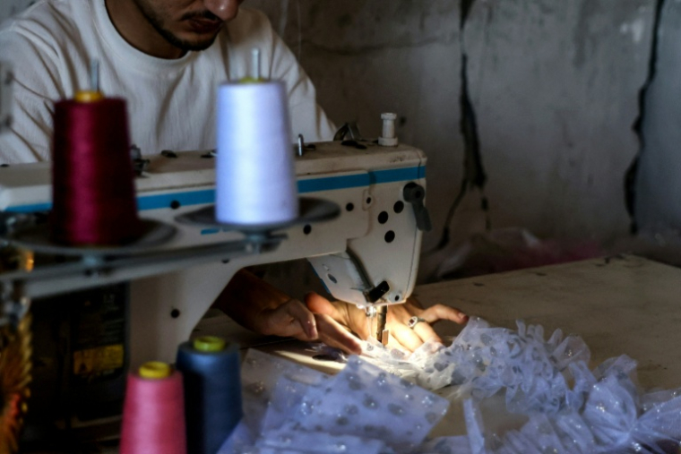 Un couturier confectionnant une robe dans sa boutique à Khan Younès dans le sud de la bande de Gaza le 13 juin 2026. ( AFP / BASHAR TALEB )