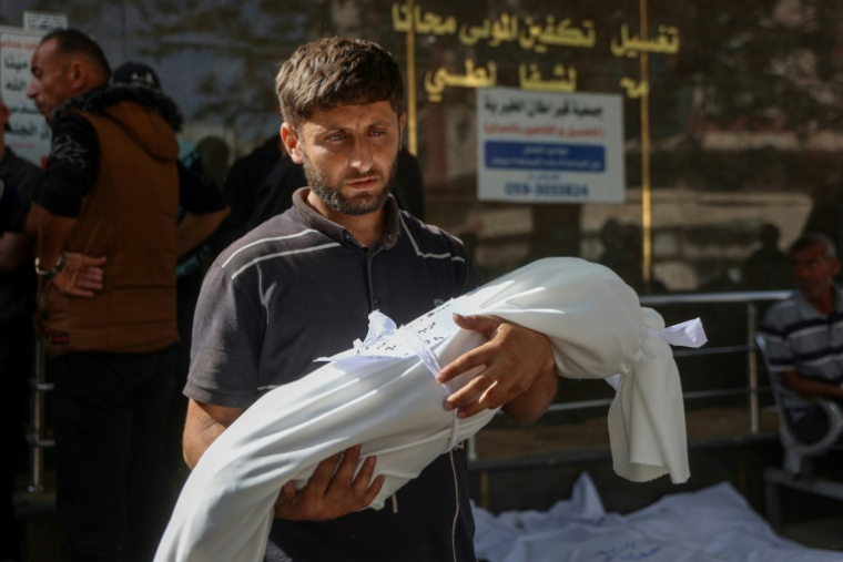 Un Palestinien porte le corps enveloppé d'un enfant tué lors d'une frappe israélienne, à l'hôpital Al-Chifa de la ville de Gaza, le 26 mai 2025 ( AFP / Omar AL-QATTAA )