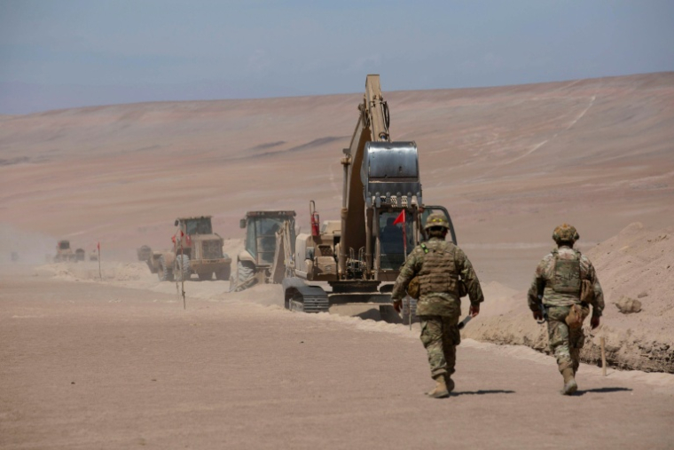Des soldats près d'engins de chantier opérant près du poste frontière de Chacalluta, à la frontière entre le Chili et le Pérou, le 16 mars 2026 ( AFP / Patricio BANDA )