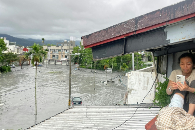 Une femme s'est réfugiée sur le toit de sa maison après la rupture d'un barrage et un glissement de terrain à Taïwan, le 23 septembre 2025 ( AFP / STR )