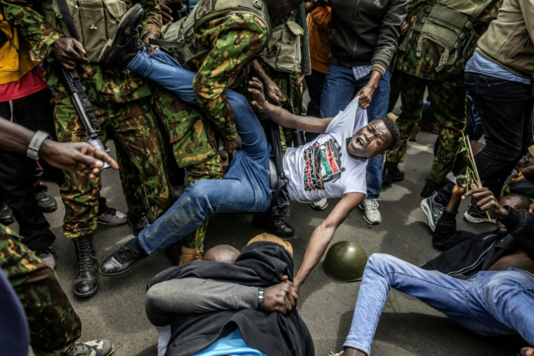 Un manifestant est arrêté par des policiers devant les bâtiments du Parlement, le 25 juin 2026 à Nairobi ( AFP / Luis TATO )