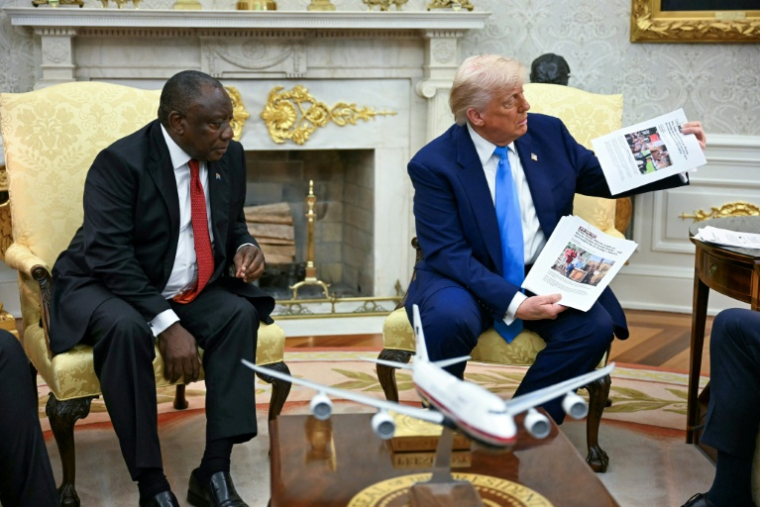 e président américain Donald Trump (d) montre des photos lors de sa rencontre avec le président sud-africain Cyril Ramaphosa dans le Bureau ovale de la Maison Blanche, à Washington, le 21 mai 2025 ( AFP / Jim WATSON )