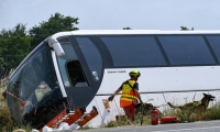 Un maître-chien du SDIS 49 intervient près d'un car qui transportait des adultes et des enfants ukrainiens avant d'avoir un accident faisant plusieurs morts sur l'A81 à Degré, en Sarthe, le 13 juin 2025 ( AFP / JEAN-FRANCOIS MONIER )