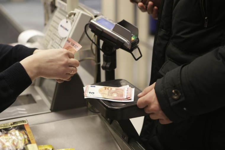 Une caissière compte des billets dans un magasin