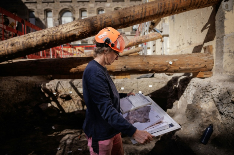 Une archéologue de la Ville de Paris examine le plan du site archéologique où un mur de Lutèce datant de l'époque gallo-romaine, a été découvert sous l'Hôtel-Dieu, dans le centre de Paris, le 23 septembre 2026 ( AFP / Simon WOHLFAHRT )