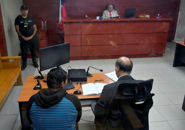 Le principal suspect (assis à gauche) des incendies meurtriers dans le sud du Chili, lors d'une audience publique à Concepción, capitale régionale du Biobio, le 23 janvier 2026 ( AFP / GUILLERMO SALGADO )