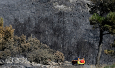 Des pompiers circulent dans une forêt dévastée par les flammes, le 8 août 2025 dans l'Aude ( AFP / Lionel BONAVENTURE )