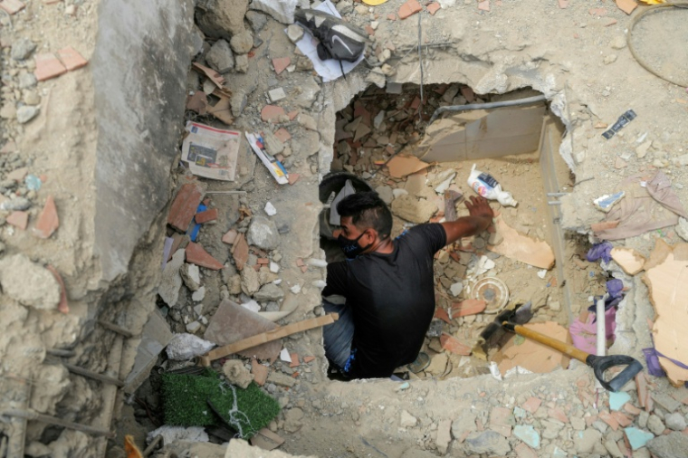 Un bénévole recherche des victimes dans les décombres de bâtiments à Caraballeda, dans l'Etat de La Guaira, après des séismes, le 28 juin 2026 au Venezuela ( AFP / Mauricio VALENZUELA )