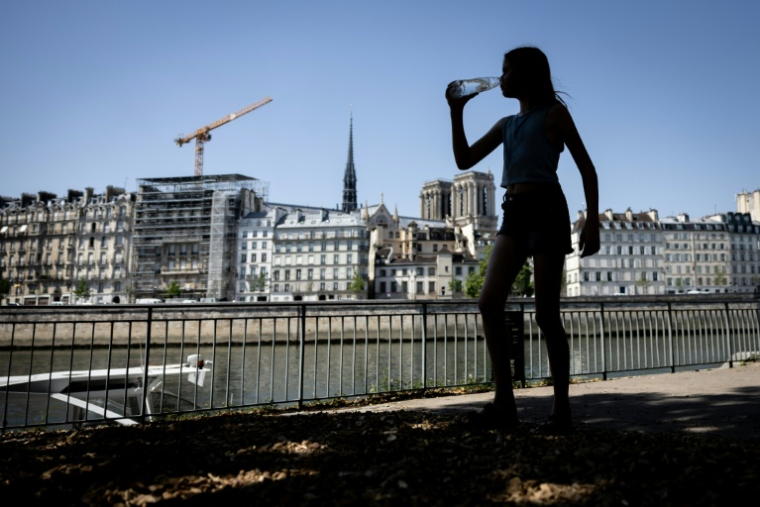 Une femme se rafraichit à l'ombre à Paris lors d'un épisode de canicule le 24 juin 2026 ( AFP / Simon WOHLFAHRT )