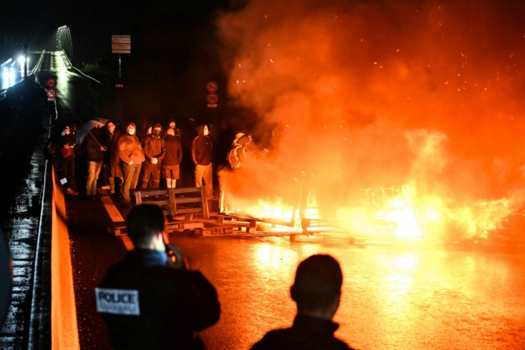 Des manifestants du mouvement "Bloquons tout" et la police près d'objets en feu sur le viaduc de Calix, à Caen, le 10 septembre 2025 ( AFP / Lou BENOIST )