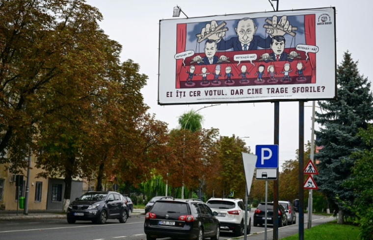 Panneau d'affichage montrant une caricature du président russe Vladimir Poutine en train de manier des marionnettes, avec le texte "Ils demandent votre vote", le 24 septembre 2025 à Ungheni (Moldavie) ( AFP / Daniel MIHAILESCU )