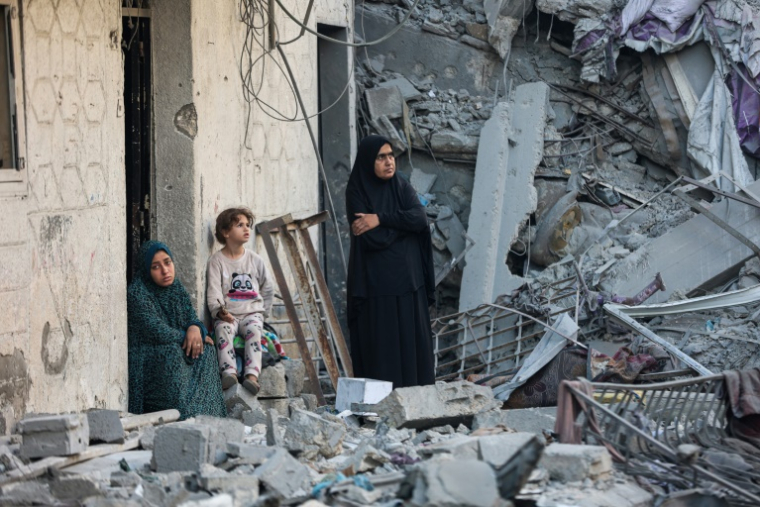 Des femmes et un enfant au milieu des décombres d'une maison détruite lors d'une frappe israélienne nocturne à Gaza, le 29 octobre 2025. ( AFP / Omar AL-QATTAA )