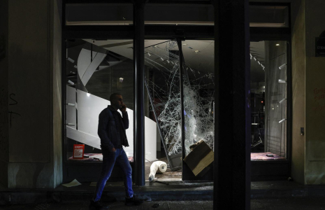 Un homme passe devant la vitrine brisée d’une boutique Diesel lors des manifestations à Paris, le 17 octobre 2026.  ( AFP / GEOFFROY VAN DER HASSELT )