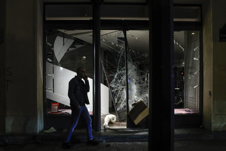 Un homme passe devant la vitrine brisée d’une boutique Diesel lors des manifestations à Paris, le 17 octobre 2026.  ( AFP / GEOFFROY VAN DER HASSELT )