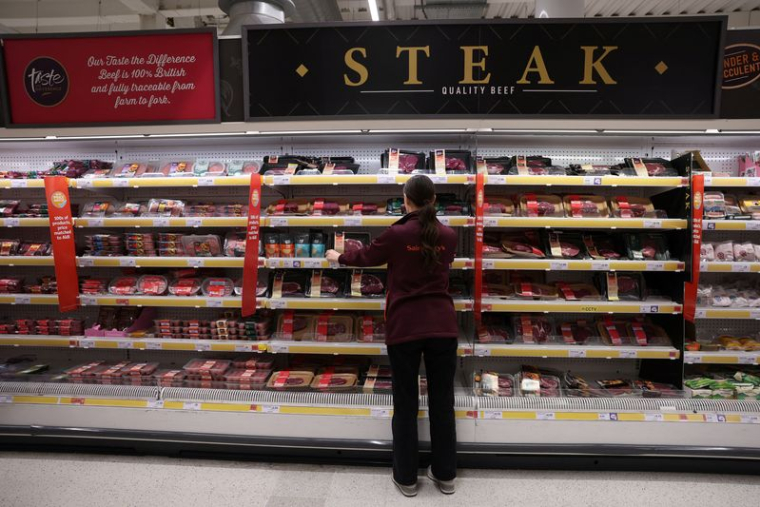 Un employé range des produits à l'intérieur d'un supermarché Sainsbury's à Londres