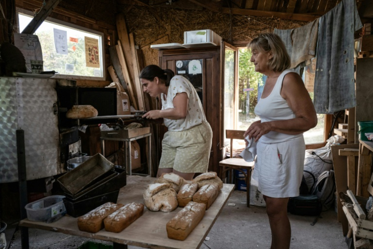 Des femmes font cuire du pain dans un four du "Quartier libres des Lentillères", une ZAD urbaine à Dijon, le 14 août 2025 en Côte d'Or ( AFP / ARNAUD FINISTRE )