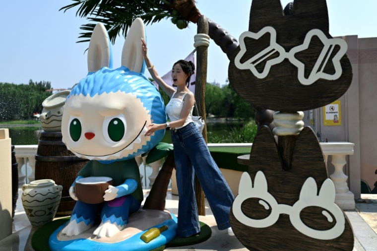 Une visiteuse se fait photographier à côté de personnages Labubu au parc d'attractions "Pop Land" de Pop Mart à Pékin, le 18 juin 2025 ( AFP / Pedro PARDO )