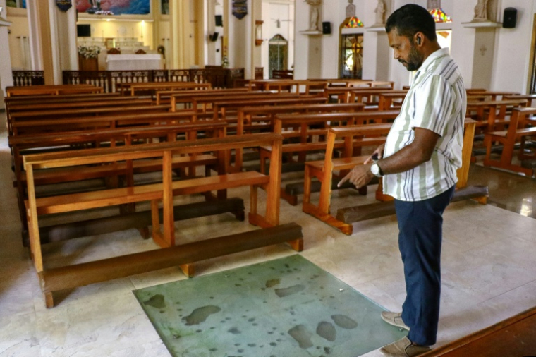 Dinal Fernando, un cadre commercial rescapé des attentats de Pâques en 2019, montre l'endroit où un kamikaze a déclenché des explosifs à l'intérieur de l'église Saint-Sébastien, dans le village de Katuwapitiya, près de Negombo, le 17 avril 2026 au Sri Lanka ( AFP / - )