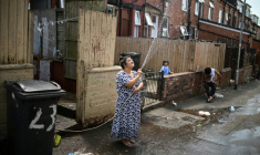 Une femme asperge une allée devant chez elle pour rafraichir à Leeds en Angleterre le 25 juin 2026 ( AFP / Oli SCARFF )