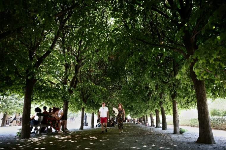Des piétons marchent à l'ombre tout en s'éventant pour se rafraîchir lors d'une vague de chaleur au Jardin du Palais-Royal à Paris, le 21 juin 2026 ( AFP / Guillaume BAPTISTE )