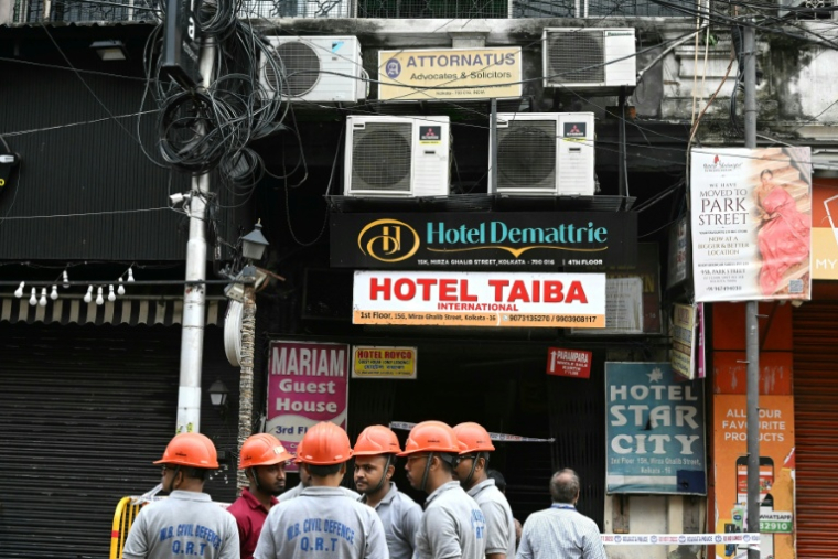 Des membres de la protection civile sur le site d'un incendie dans un hôtel à Calcutta, le 19 août 2026 en Inde ( AFP / Dibyangshu SARKAR )