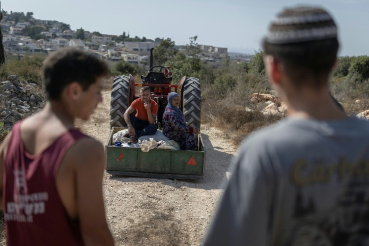 Des colons israéliens font face à une famille palestinienne, lle 13 octobre 2026 en Cisjordanie occupée en pleine récolte d'olives ( AFP / Ilia YEFIMOVICH )
