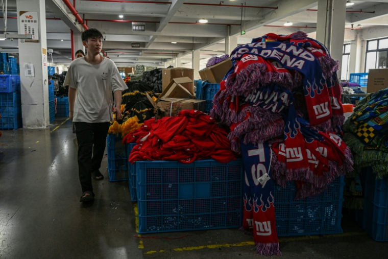 Un employé passe devant une pile de produits dans une usine qui fabrique des chapeaux et des écharpes à Yiwu, dans la province du Zhejiang, dans l'est de la Chine, le 18 septembre 2025 ( AFP / Jade GAO )