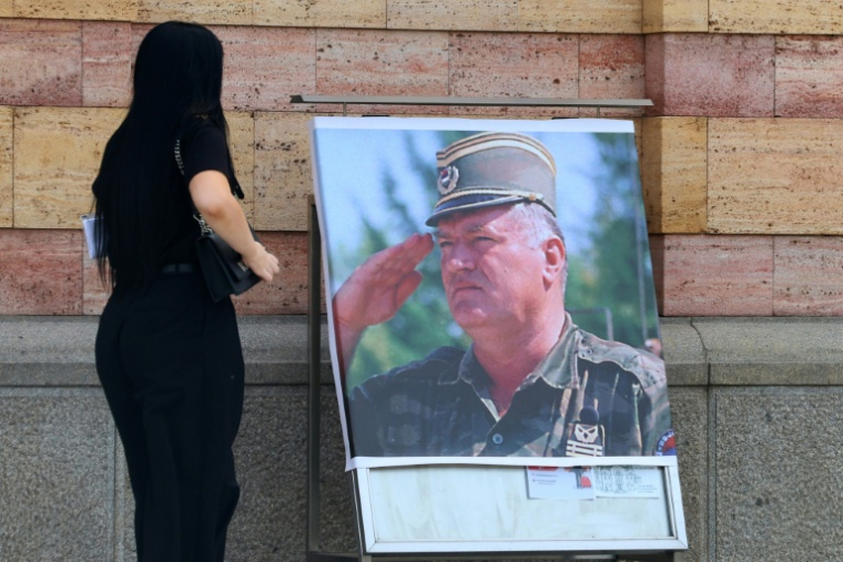 Une femme regarde un portrait de l'ancien chef militaire des Serbes de Bosnie, Ratko Mladić, devant la cathédrale orthodoxe de Banja Luka, en Bosnie, le 28 août 2026, au lendemain de sa mort à l'âge de 84 ans dans un hôpital pénitentiaire de La Haye ( AFP / STRINGER )