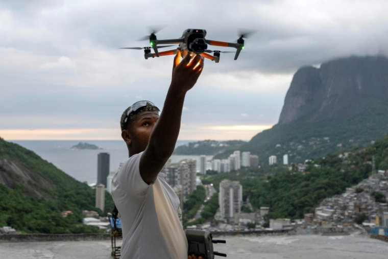 Le pilote de drone Pedro Lucas récupère son drone après avoir filmé un touriste pour les réseaux sociaux au célèbre point de vue touristique "Porta do Ceu" (Porte du Ciel) dans la favela de Rocinha, à Rio de Janeiro, au Brésil, le 5 mars 2026 ( AFP / Pablo PORCIUNCULA )