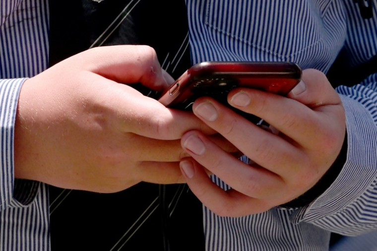 Un étudiant utilise son téléphone portable à Melbourne en Australie, le 27 novembre 2024 ( AFP / William WEST )