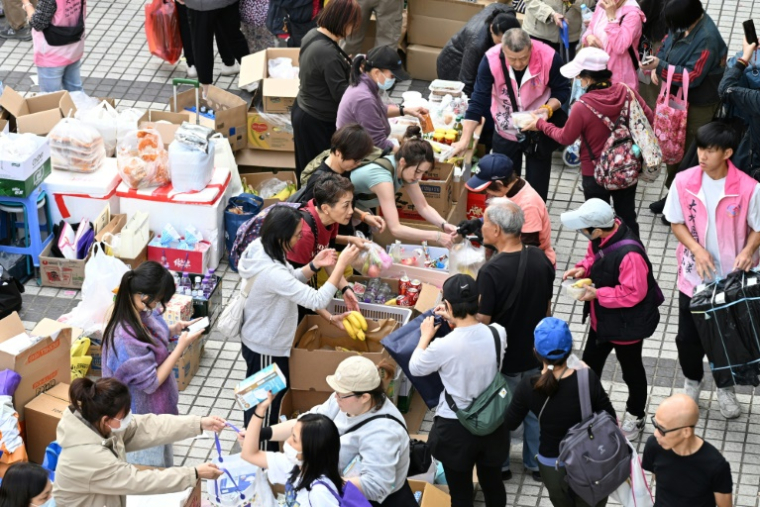 Des volontaires distribuent de la nourriture et des boissons après qu'un important incendie a ravagé plusieurs immeubles d'appartements du complexe résidentiel Wang Fuk Court,  à Hong Kong, le 27 novembre 2025 ( AFP / Peter PARKS )