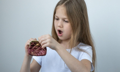 une petite fille avec un porte monnaie (Crédits: Adobe Stock)