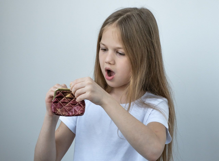 une petite fille avec un porte monnaie (Crédits: Adobe Stock)