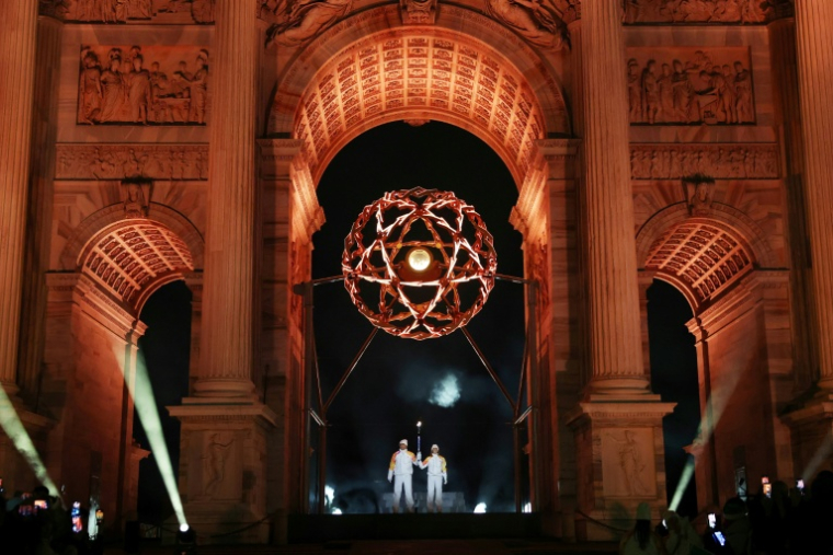 Les légendes italiennes du ski Deborah Compagnoni et Alberto Tomba allument la vasque olympique sous l'Arc de la paix à Milan, lors de la cérémonie d'ouverture des Jeux de Milan Cortina, le 6 février 2026 ( POOL / Jamie Squire )