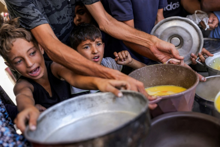Des enfants palestiniens font la queue pour recevoir des repas d'une organisation caritative locale à Gaza-ville, le 14 juillet 2025 ( AFP / BASHAR TALEB )