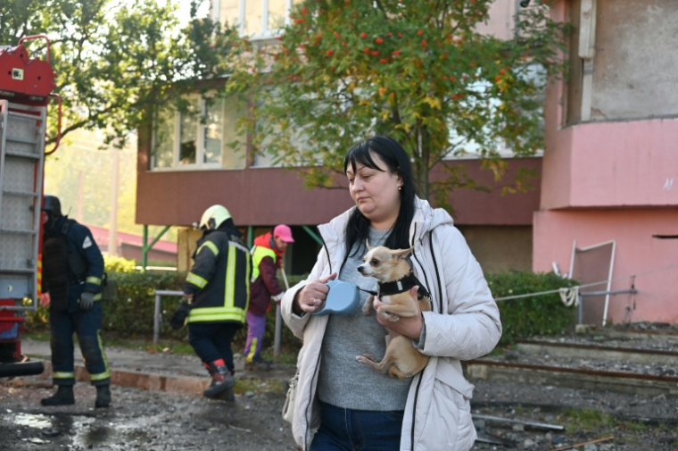 Une femme avec son chien devant un bâtiment touché par une attaque russe à Kharkiv, Ukraine, le 12 octobre 2026 ( AFP / SERGEY BOBOK )