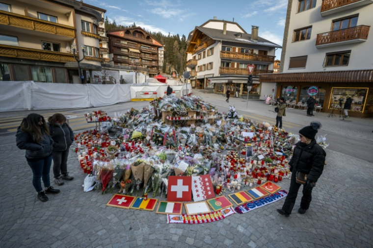 Des fleurs, des messages et des drapeaux déposés sur un mémorial improvisé le 6 janvier 2026 en hommage aux victimes de l'incendie mortel d'un bar dans la nuit du nouvel an à Crans-Montana, en Suisse ( AFP / Fabrice COFFRINI )
