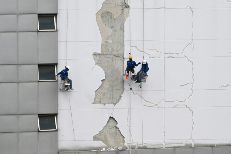 Des ouvriers réparent les dégâts sur le mur d'une tour Bangkok, le 3 avril 2025, suite au tremblement de terre du 28 mars qui a frappé le centre de la Birmanie et la Thaïlande. ( AFP / MANAN VATSYAYANA )