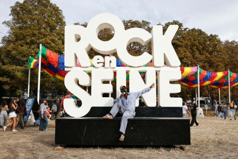 Un festivalier pose devant l'enseigne du festival Rock en Seine à Saint-Cloud dans les Hauts-de-Seine le 26 août 2026 ( AFP / SIMON WOHLFAHRT )