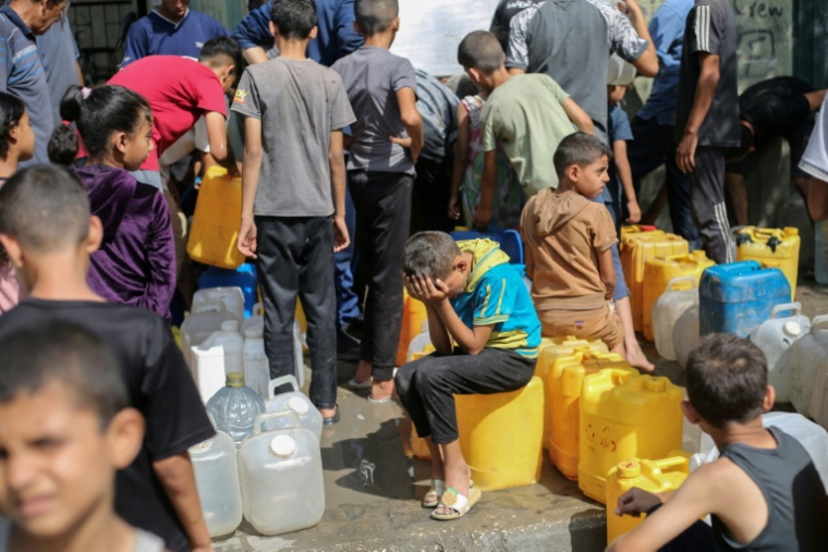 Des enfants palestiniens affluent à une distribution d'eau à Nousseirat, dans le centre de la bande de Gaza, le 4 septembre 2025 ( AFP / Eyad BABA )