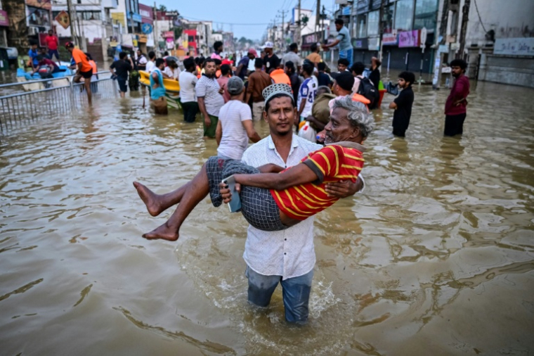 Des habitants dans une rue inondée après des fortes pluies à Wellampitiya, dans la banlieue de Colombo, le 30 novembre 2025 au Sri Lanka ( AFP / Ishara S. KODIKARA )
