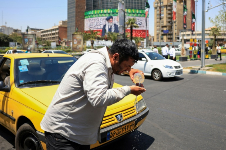 Un chauffeur de taxi se mouille le visage avec de l'eau pour se rafraîchir dans une rue de Téhéran, lors d'une vague de chaleur en Iran, le 22 juillet 2025 ( AFP / - )
