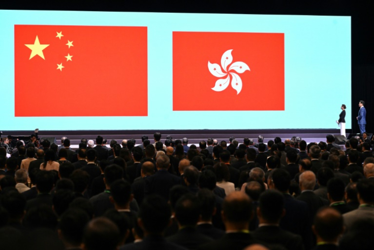 Les drapeaux chinois et hongkongais apparaissent sur un grand écran durant une cérémonie pour le cinquième anniversaire de la promulgation de la loi sur la sécurité nationale, le 21 juin 2025 à Hong Kong ( AFP / Peter PARKS )